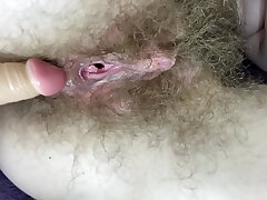 Hairy girl fucks her raw big clit beaver with faux-cock in close up